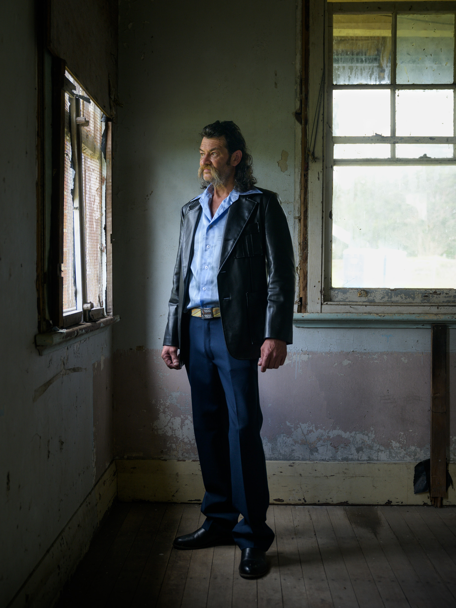 Man in a leather jacket standing in an abandoned homestead, rural Australia — portrait photography by Matthew Abbott