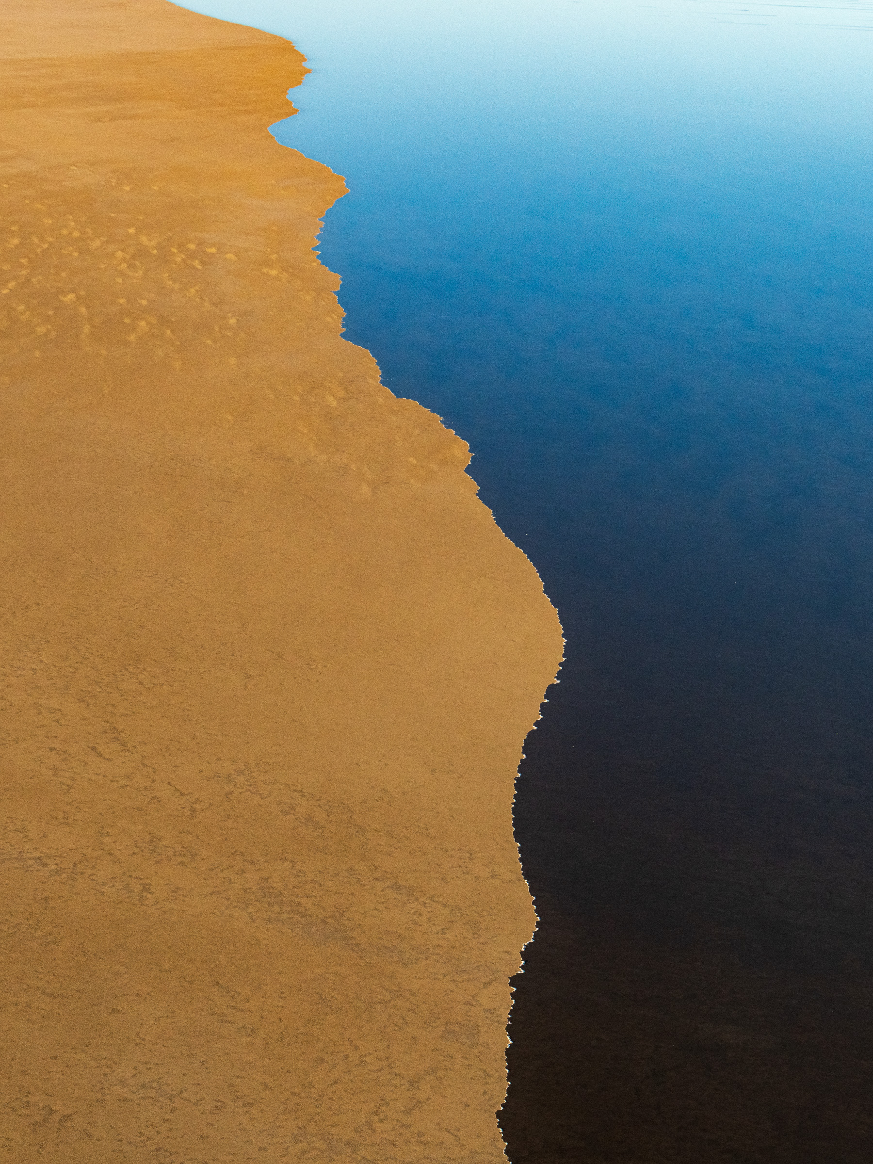 Aerial view of water meeting arid land in the Australian outback — landscape photography by Matthew Abbott